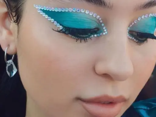 Occhi con ombretto blu elettrico e strass scintillanti, un look che fa make up euphoria. Orecchino pendente con cristallo.