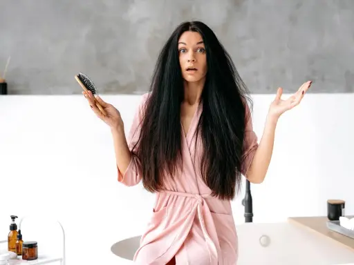 Donna con capelli elettrizzati e spazzola in mano, espressione sorpresa.