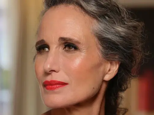 Donna con capelli grigi e trucco impeccabile, labbra rosse vivaci. Un esempio di come truccarsi a 50 anni con eleganza.