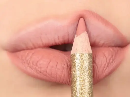 Matita glitterata color oro definisce il contorno delle labbra con un tratto preciso, creando un effetto overline labbra impeccabile.