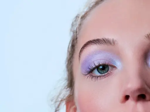 Occhio con ombretto lilla scintillante, ciglia lunghe e sopracciglia definite. Un trucco per serata elegante che cattura lo sguardo.