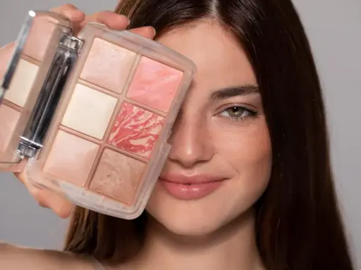 Una donna sorride mostrando una palette di make up elegante con sei cialde di diverse tonalità rosate e luminose.