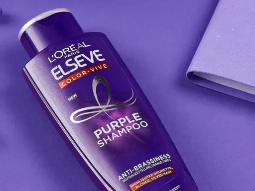 Flacone di shampoo viola L'Oréal Elseve Color-Vive, con auricolari e quaderno viola. Lo shampoo antigiallo schiarisce i capelli, neutralizzando i toni indesiderati.