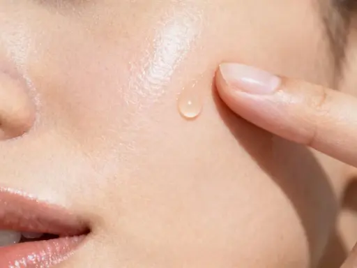 Goccia di siero sulla pelle, un tocco delicato. La niacinamide a cosa serve? Migliora la barriera cutanea e riduce le imperfezioni.