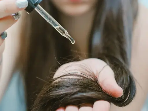 Goccia di olio di ricino su capelli scuri. Scopri a cosa serve l'olio di ricino per la cura dei capelli e della pelle.