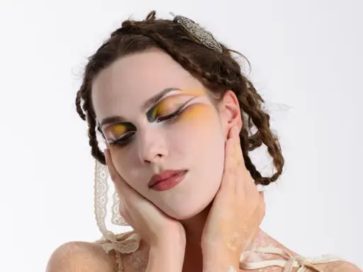 Modella con trucco artistico audace, occhi colorati e dettagli dorati. Idee trucco artistico per un look da sogno.