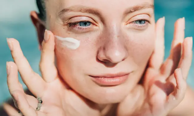 Donna applica crema sul viso. Attenzione: crema solare tutti i giorni fa male alla pelle.