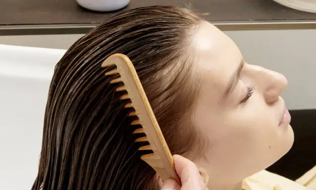 Una mano pettina delicatamente i capelli bagnati, sciogliendo eventuali nodi ai capelli dietro la nuca per una chioma fluente.