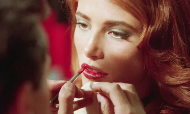 Dettagli di un trucco labbra perfetto: un pennellino applica rossetto rosso brillante, un segreto per non far sbavare il rossetto.