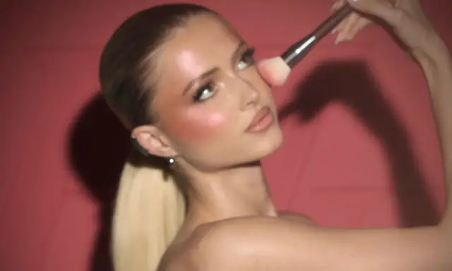 Donna bionda con un pennello applica il blush in polvere sulle guance per un look radioso.