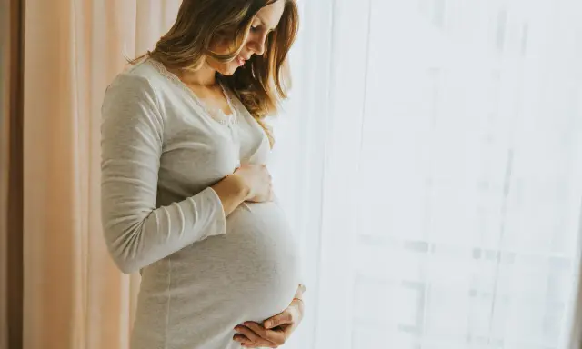 Donna incinta accarezza il pancione, pensando ai benefici dell'acido ialuronico in gravidanza per la pelle.