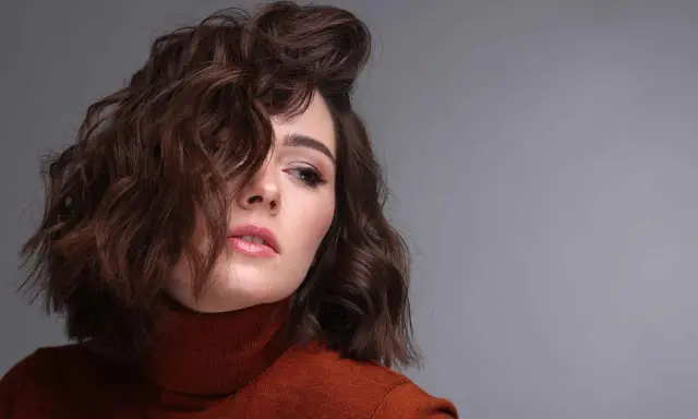 Modella con capelli castani mossi, un look ispirato a come fare i capelli mossi con onde morbide e naturali.