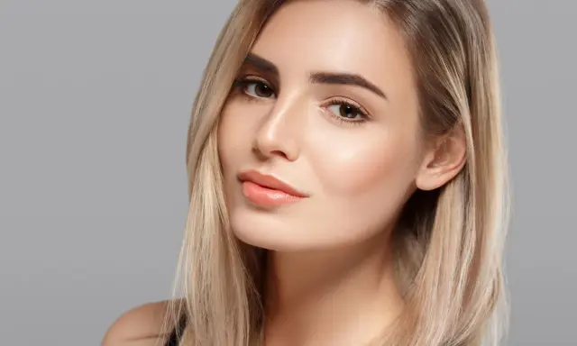 Volto di donna con capelli biondi e un make up naturale che esalta la sua bellezza.