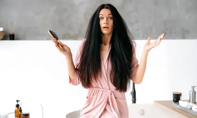 Donna con capelli elettrizzati e spazzola in mano, espressione sorpresa.