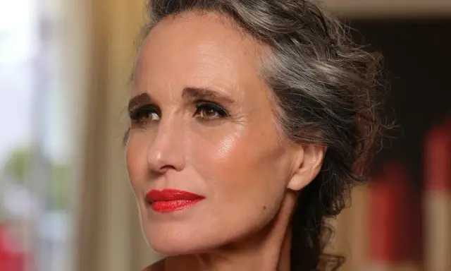 Donna con capelli grigi e trucco impeccabile, labbra rosse vivaci. Un esempio di come truccarsi a 50 anni con eleganza.
