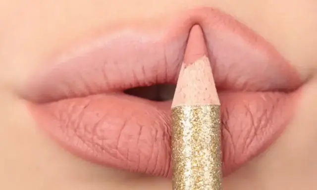 Matita glitterata color oro definisce il contorno delle labbra con un tratto preciso, creando un effetto overline labbra impeccabile.