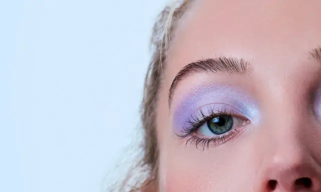 Occhio con ombretto lilla scintillante, ciglia lunghe e sopracciglia definite. Un trucco per serata elegante che cattura lo sguardo.