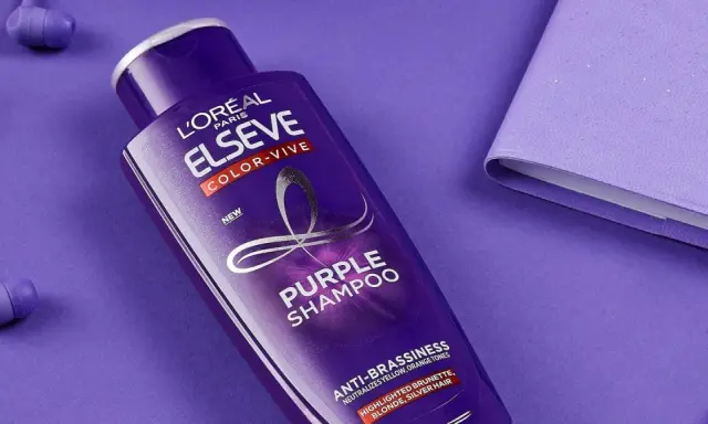 Flacone di shampoo viola L'Oréal Elseve Color-Vive, con auricolari e quaderno viola. Lo shampoo antigiallo schiarisce i capelli, neutralizzando i toni indesiderati.