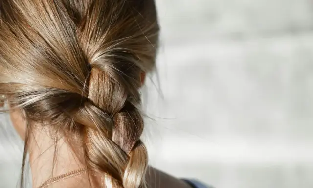 Capelli biondi intrecciati in una treccia. Per chi ha capelli grassi, la frequenza di lavaggio è una questione personale.