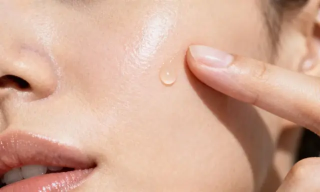 Goccia di siero sulla pelle, un tocco delicato. La niacinamide a cosa serve? Migliora la barriera cutanea e riduce le imperfezioni.