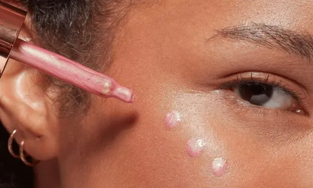 Gocce di illuminante rosa applicate sul viso con un contagocce, per un look radioso.