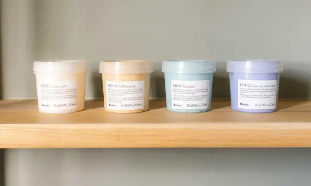 Quattro maschere per capelli Davines su uno scaffale. Scopri quanto tenerla per un trattamento ottimale.