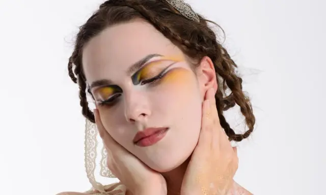 Modella con trucco artistico audace, occhi colorati e dettagli dorati. Idee trucco artistico per un look da sogno.