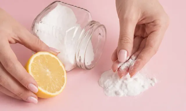Mani che preparano una maschera fai-da-te con limone e bicarbonato per scoprire come togliere i brufoli dal viso.