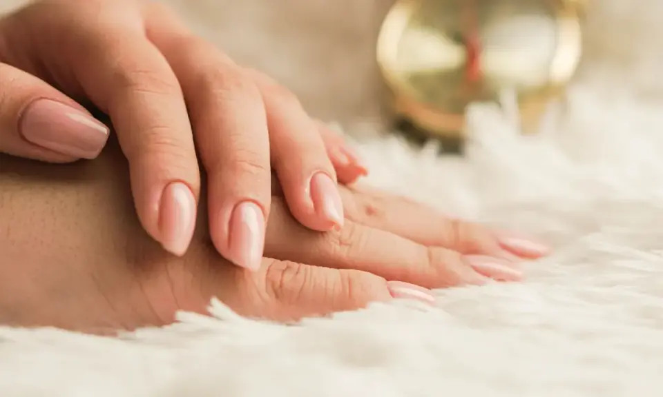 Mani curate con smalto rosa tenue, un esempio di come nutrire le unghie per una bellezza impeccabile.