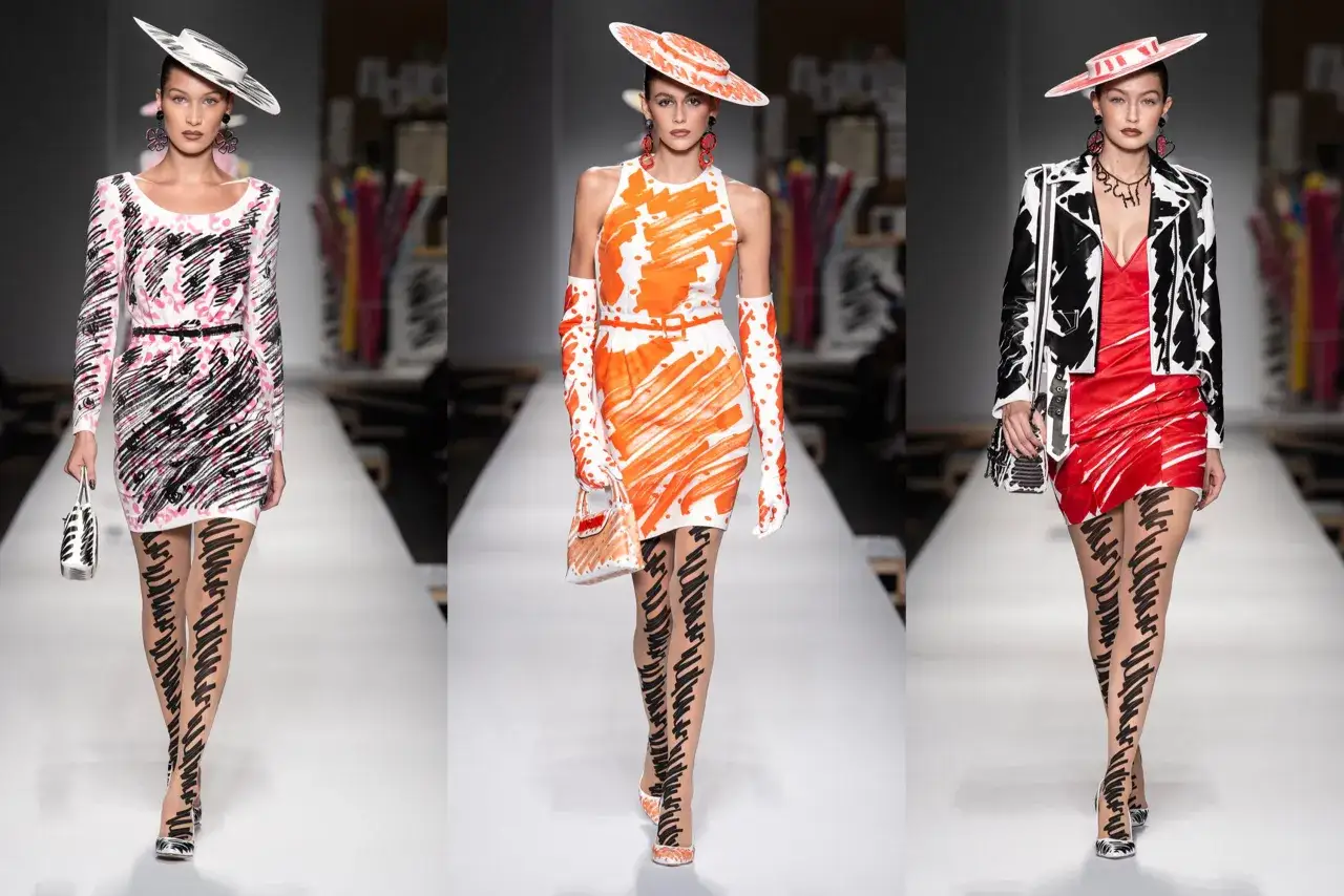 Modelli sfilano con abiti Moschino donna con stampe astratte e calze a fantasia.