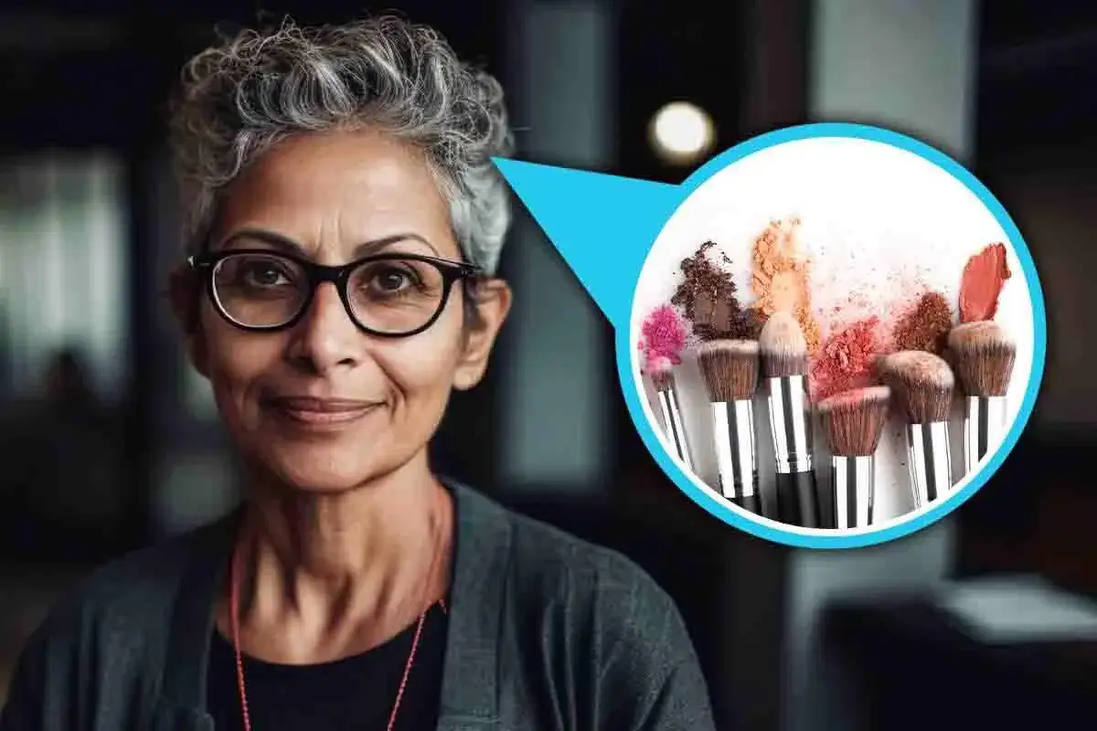 Donna con capelli sale e pepe sorride, con un cerchio che mostra pennelli da trucco e ombretti colorati.