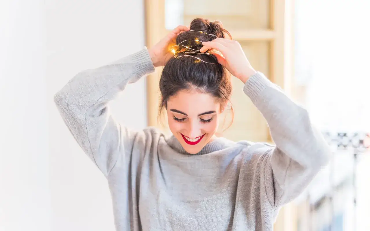Ragazza sorridente con capelli raccolti in uno chignon luminoso, un'idea per come avere capelli perfetti e luminosi.
