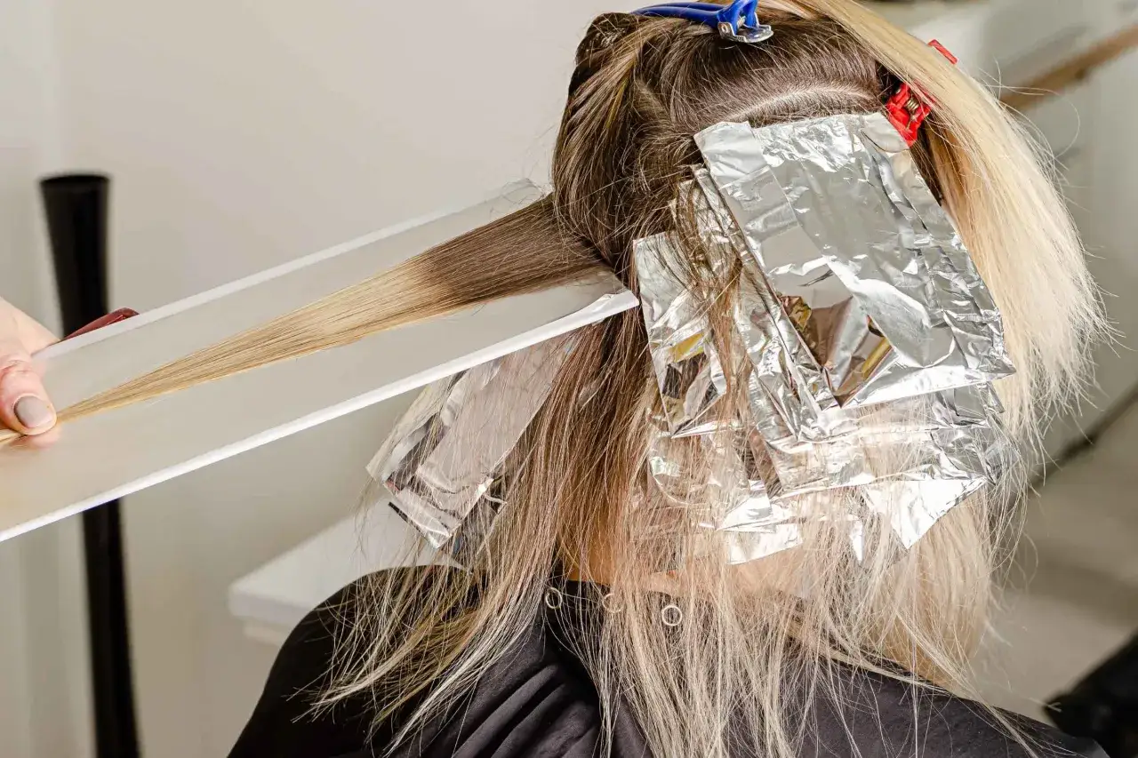 Applicazione di fogli argentati per il trattamento capelli decolorati, creando riflessi biondi luminosi.